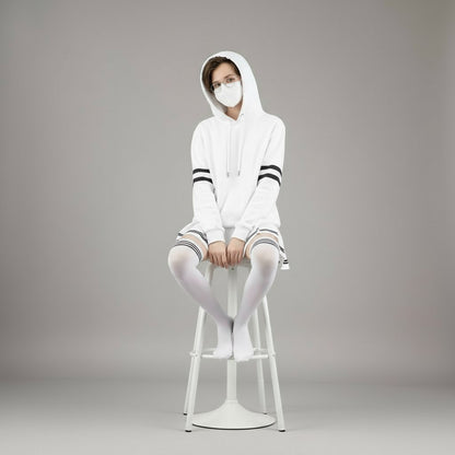 Femboy wearing a white hoodie with stripes, pleated skirt, and stockings on a gray background